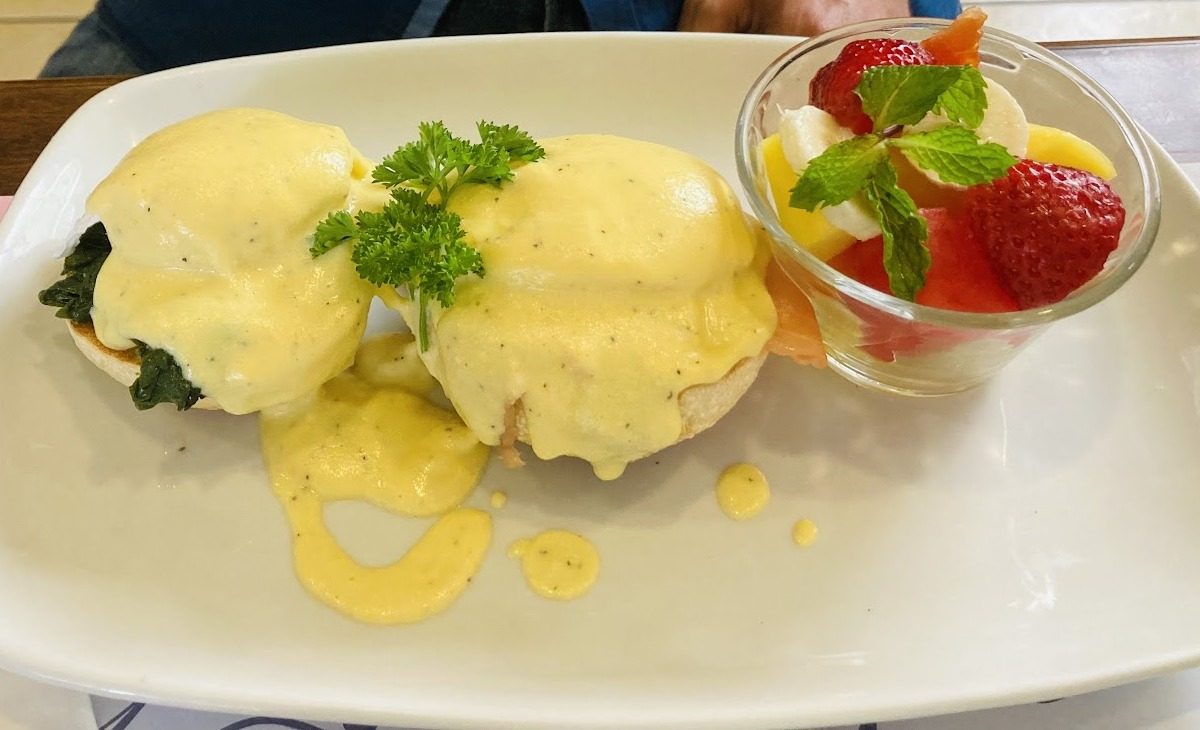 Huevos benedictinos con espinaca y una copa de frutas frescas, servidos en el restaurante