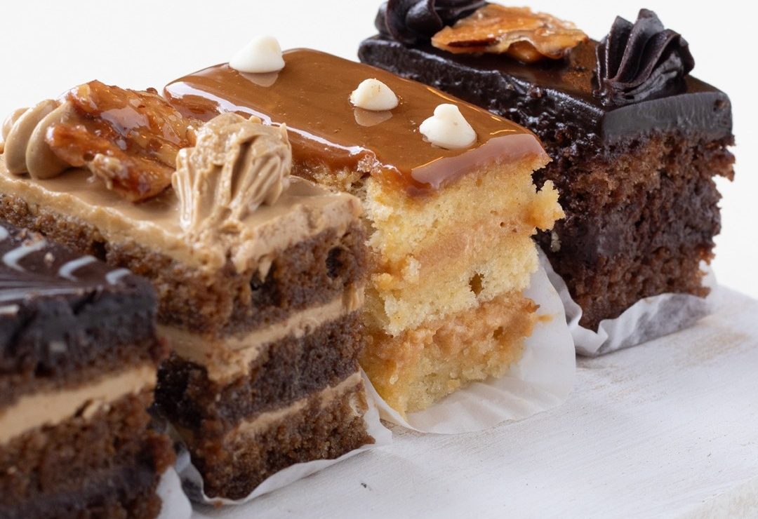 Tres cortes de pastel de la vitrina, con capas de crema y coberturas de caramelo y chocolate